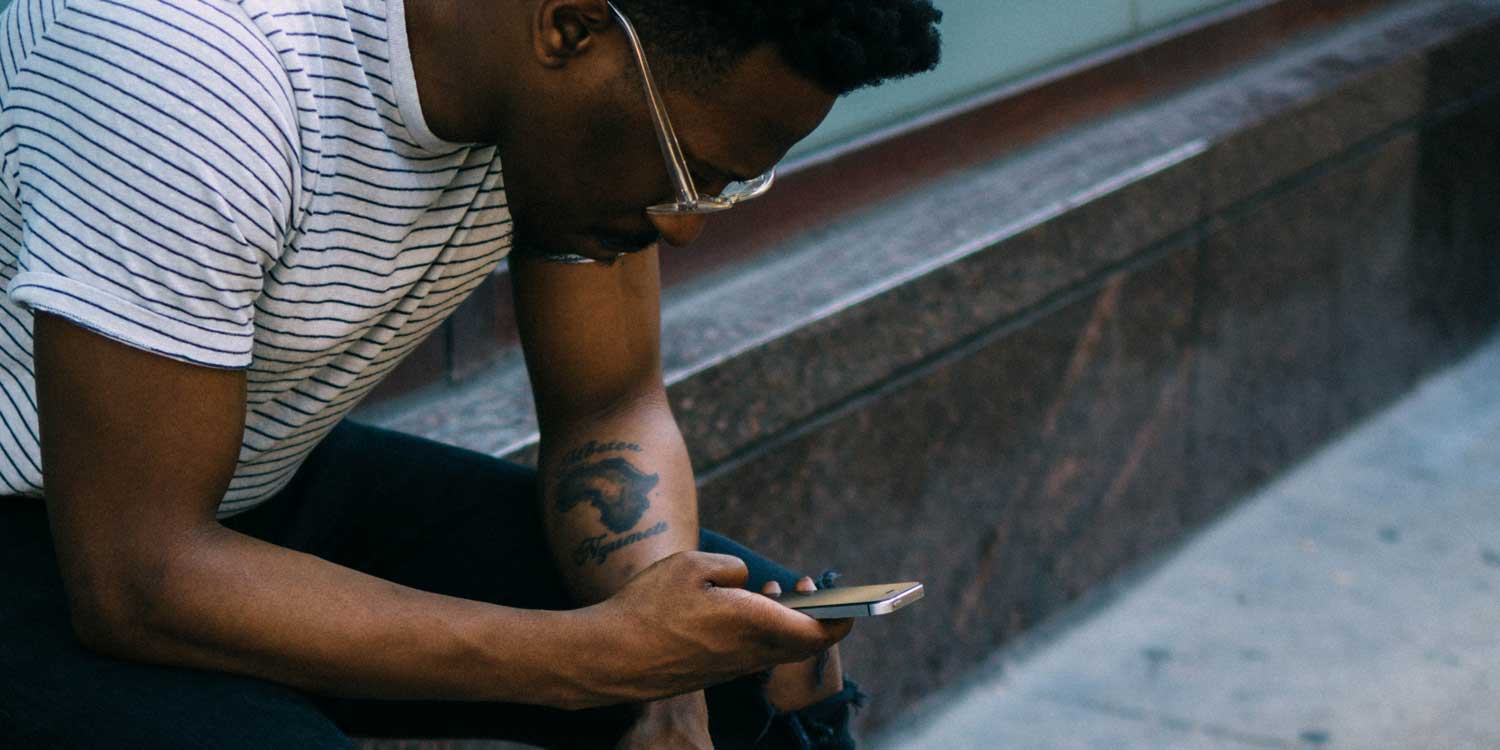 man looking at phone on sidewalk