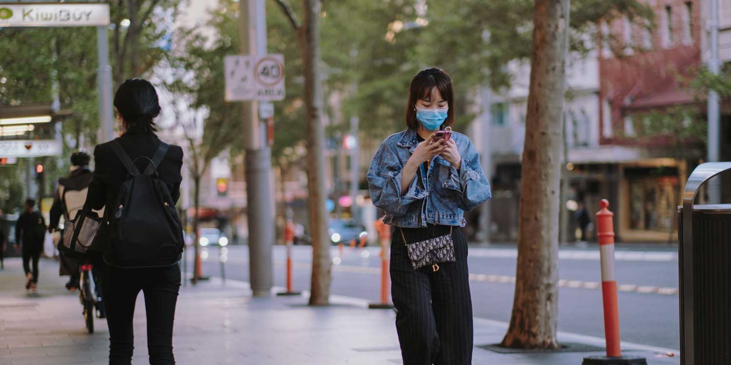 masked woman walking phone